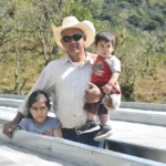 Coffee producer Remiery Orlando Carabajal by drying beds at his farm La Casa in Honduras with his family