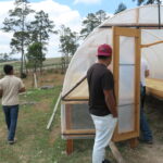 Producers and farmers inspecting coffee beans drying on rasied beds at Las Botijas